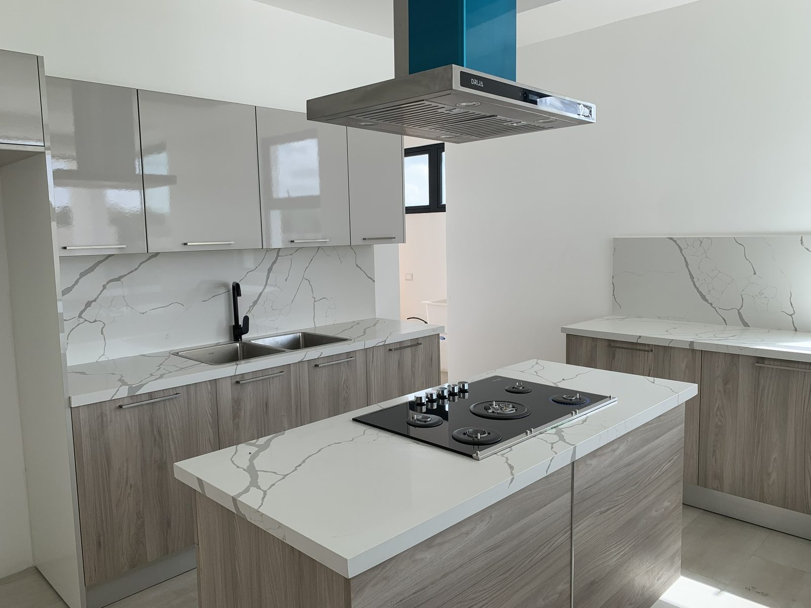 Cocina con isla central, tope en cuarzo y campana